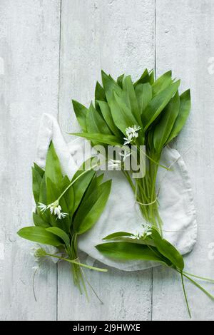 Photo de studio de serviette et de feuilles de ramson fraîches reposant sur une surface en bois Banque D'Images