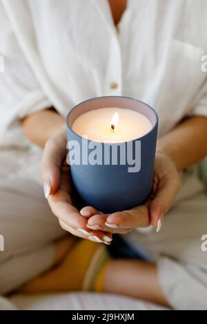 Mains d'une femme tenant une bougie parfumée à la maison Banque D'Images