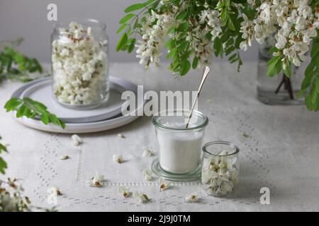 Fleurs d'acacia et sucre dans un pot sur fond gris. Banque D'Images