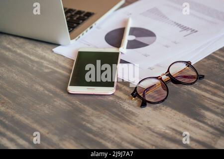 Tableaux, graphiques et diagrammes imprimés financiers avec verres sur table Banque D'Images