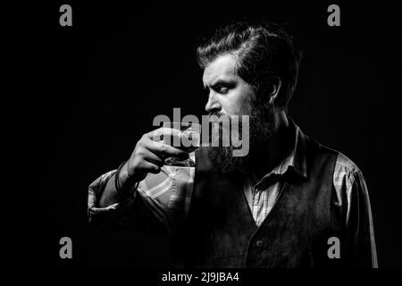 Homme plein de confiance et bien habillé avec un verre de whisky. L'homme d'affaires se débarrasse du stress avec le whisky. Homme d'affaires barbu en costume élégant avec verre de Banque D'Images