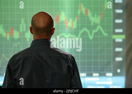 Homme d'âge mûr méconnaissable travaillant dans la société de bourse regardant le graphique, vue arrière de prise de vue Banque D'Images