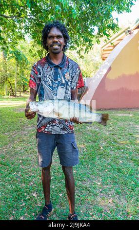 Jeune aborigène souriant tenant un poisson barramundi pendant le festival Taste of Kakadu, Cooinda, parc national de Kakadu, territoire du Nord, territoire du Nord, AUS Banque D'Images