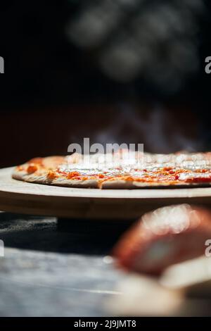 Pizza prête à l'emploi sur un stand. Le processus de fabrication de pizza maison. Le concept de restauration rapide maison. Photo verticale. Banque D'Images