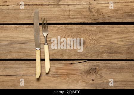 Le vieux couteau et la fourchette reposent sur un fond en bois, les couverts dans la cuisine sur la table, la mise en place de la table Banque D'Images