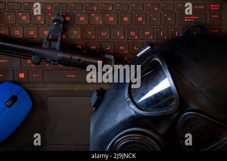 Arme militaire et souris d'ordinateur et masque noir de gaz se trouvent sur le clavier de l'ordinateur portable avec rétroéclairage rouge, attaque de hacker, cyber-sécurité Banque D'Images