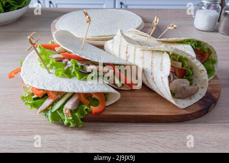 tortillas ou buritto faits maison sur un panneau de bois pour servir des aliments. remplissage de légumes mûrs et de filets de poulet. plats végétariens Banque D'Images