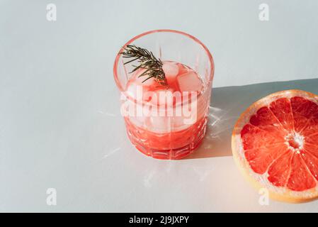 Jus de pamplemousse rouge frais avec ingrédients à la lumière du soleil. Vue de dessus, espace de copie. Banque D'Images