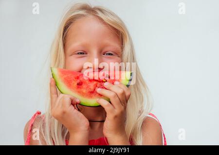 Jeune fille blonde peau bronzée boire un jus de détox maison saine alimentation.papaye, ananas, fruit dragon, orange sur une table blanche à côté d'un Banque D'Images