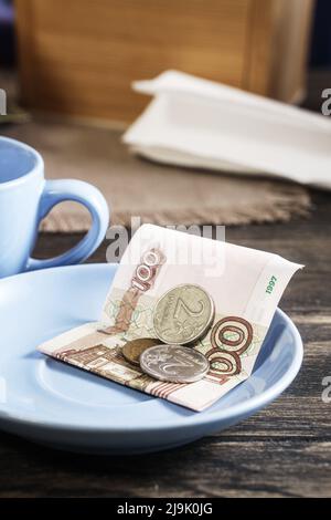 Pourboires ou pourboires au restaurant, billets et pièces de monnaie russes sur l'assiette Banque D'Images