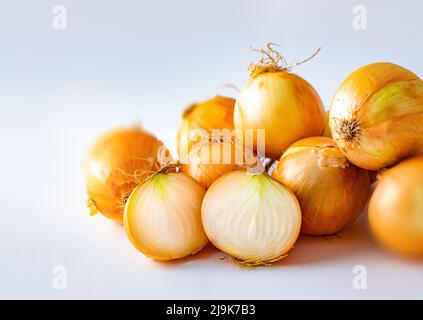 Oignons bruns isolés sur fond blanc.oignons frais en bulbe cru.oignons bruns et tranches sur planche à découper en bois.fond sain d'aliments. Banque D'Images