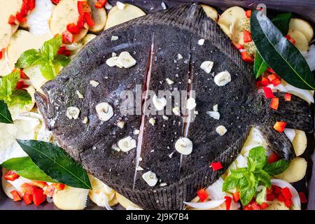 Poisson Turbot entier cuit au four avec pommes de terre, poivron et herbes aromatiques. Fruits de mer frais. Banque D'Images