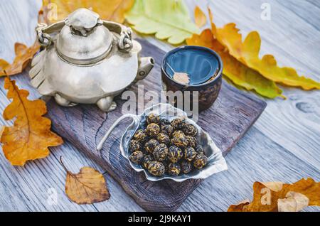 Le thé chinois dans une vie d'automne encore. Une théière en métal originale en forme de tortue, une tasse de thé et de thé sec dans un support en forme de feuille sur la table Banque D'Images