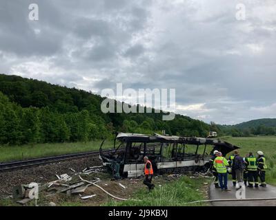 Blaustein, Allemagne. 24th mai 2022. Un bus brûlé se trouve à côté d'une ligne de chemin de fer en arrière-plan un train qui avait heurté le bus plus tôt. (À dpa 'train collides avec bus près d'Ulm - plusieurs blessés') Credit: Sebastian Schlenker/dpa/Alamy Live News Banque D'Images