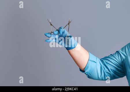 La main du médecin dans un gant médical contient des instruments médicaux. Ciseaux chirurgicaux. Proctologie. Banque D'Images