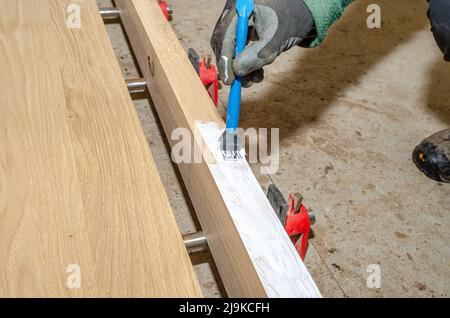 Peindre une surface en bois avec un pinceau. Main de maître avec pinceau. Vue rapprochée Banque D'Images