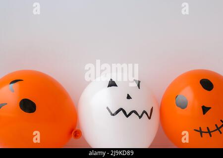 Les jacks peints font face aux ballons. Préparation des boules orange et blanches pour halloween. Activités à la maison pour Halloween. Jouets faits main artisanat pour enfants Banque D'Images