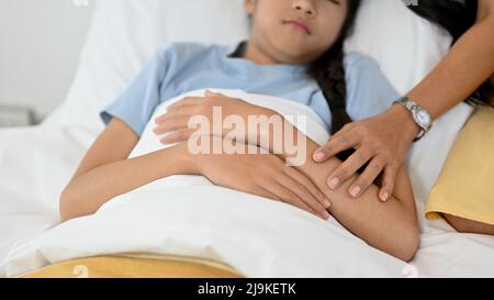 Gros plan, maman vérifiant la température de sa fille. Petite fille couchée au lit, prenant une sieste, se reposant de sa maladie. Banque D'Images