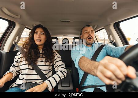 Couple effrayé conduisant une voiture, portrait avant, vue du pare-brise Banque D'Images