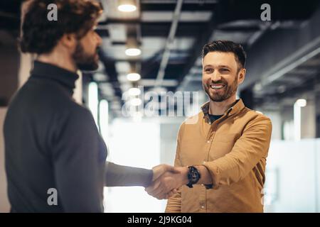 Des entrepreneurs heureux et confiants qui se brandient aux mains pour conclure un accord ou un accord dans un immeuble de bureaux moderne Banque D'Images