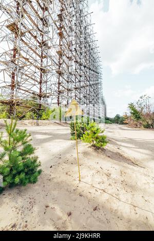 Panneau de signalisation de rayonnement dangereux devant le radar Duga dans la zone d'exclusion de Pripyat Tchernobyl, un jour d'été Banque D'Images