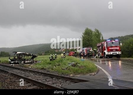 Blaustein, Allemagne. 24th mai 2022. Les secouristes du service des incendies se trouvent à côté d'un bus brûlé à un passage à niveau près de Blaustein, près d'Ulm. Le bus est entré en collision avec un train là-bas et plusieurs personnes ont été grièvement blessées. (À dpa 'train collides avec bus près d'Ulm - plusieurs blessés') Credit: Sebastian Schlenker/dpa/Alamy Live News Banque D'Images