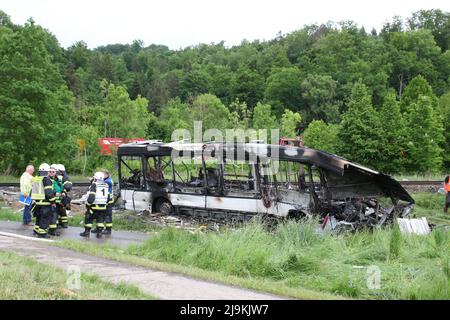 Blaustein, Allemagne. 24th mai 2022. Les secouristes se tiennent à côté d'un bus brûlé près de Blaustein, près d'Ulm. L'autobus est entré en collision avec un train à un passage à niveau et plusieurs personnes ont été grièvement blessées. (À dpa 'train collides avec bus près d'Ulm - plusieurs blessés') Credit: Sebastian Schlenker/dpa/Alamy Live News Banque D'Images