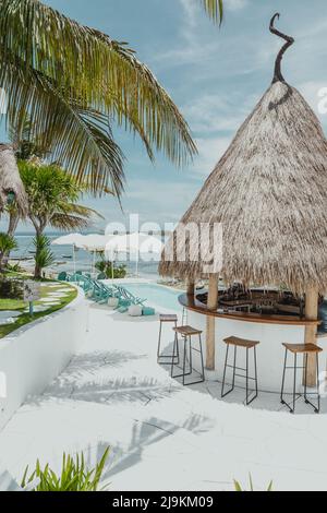 Refuge de bar tropical sur l'île tropicale de Lembongan à Bali Indonésie, lors d'une journée d'été ensoleillée avec parasols de piscine et palmiers Banque D'Images
