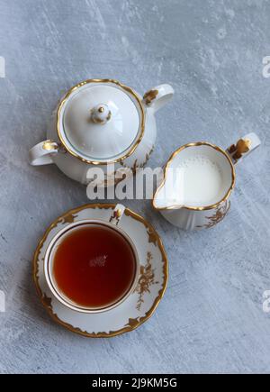 Thé avec roses photo de gros plan. Tisane dans une petite tasse de céramique blanche sur une table. Arrière-plan gris clair avec espace de copie. Banque D'Images