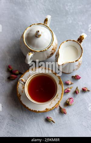 Thé avec roses photo de gros plan. Tisane dans une petite tasse de céramique blanche sur une table. Arrière-plan gris clair avec espace de copie. Banque D'Images