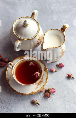 Thé avec roses photo de gros plan. Tisane dans une petite tasse de céramique blanche sur une table. Arrière-plan gris clair avec espace de copie. Banque D'Images