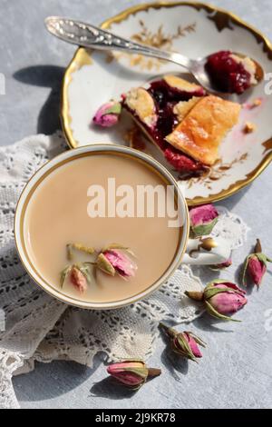 Thé avec roses photo de gros plan. Tisane dans une petite tasse de céramique blanche sur une table. Arrière-plan gris clair avec espace de copie. Banque D'Images