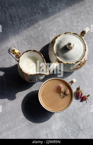 Thé avec roses photo de gros plan. Tisane dans une petite tasse de céramique blanche sur une table. Arrière-plan gris clair avec espace de copie. Banque D'Images