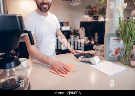 Concept de comptoir de nettoyage à la cafétéria. Un barista masculin travaille au bar et le garde propre. Banque D'Images