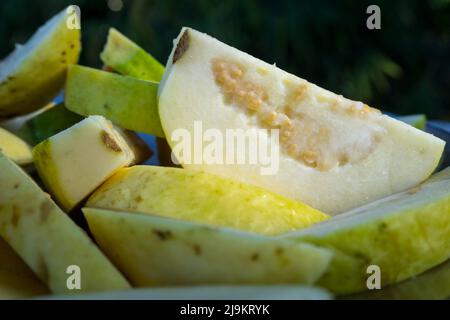 Un gros plan de salade de goyave servi avec un mélange indien de sel vert sur une assiette blanche. Banque D'Images