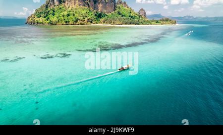 Eau turquoise tropicale avec un bateau à longue queue thaïlandais passant devant un récif de corail et l'île de Ko Poda dans la mer d'Andaman de Krabi Thaïlande Banque D'Images