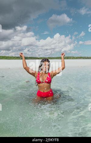 Jeune femme asiatique de couleur turquoise dans l'eau de l'océan avec un bikini rouge sur l'île privée de Leebong en Indonésie avec belle plage de sable blanc Banque D'Images