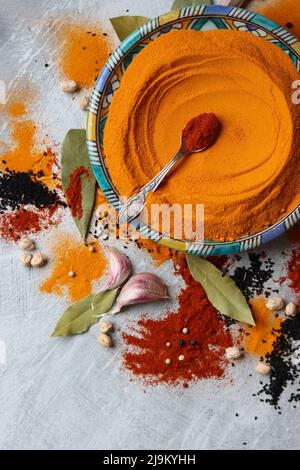 Encore plus coloré avec de la poudre curcuma sur une assiette faite à la main bleue. Photo en gros plan de différentes épices sur fond gris clair. Banque D'Images