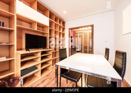 Bureau professionnel avec table de réunion en métal chromé et en verre avec chaises en similicuir noir, étagères en bois à plusieurs compartiments, parquet Banque D'Images