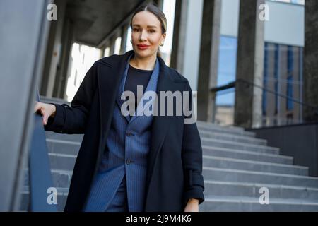 Femme d'affaires dans des vêtements élégants sur les escaliers d'un bâtiment moderne Banque D'Images