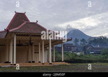 Le mont Merapi rasse des cendres volcaniques et des matériaux vus du village de Girikerto à Sleman, Yogyakarta, Indonésie avec le bâtiment Joglo Pendopo. Banque D'Images