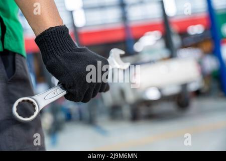 Auto Mechanic tenant une clé dans un centre de réparation automobile. Banque D'Images