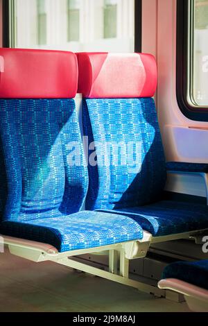 Sièges en tissu vide bleu rouge gros plan, intérieur des trains de voyageurs ou tramway ferroviaire. Concept de transport public Banque D'Images