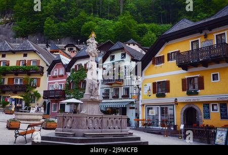 Vue panoramique sur le quartier historique de la place centrale de Hallstatt avec statue entourée de maisons traditionnelles colorées et de restaurants à Hallstatt Banque D'Images