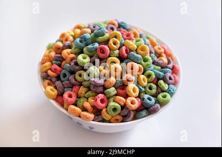 Des boucles de céréales aux fruits délicieuses et nutritives avec du lait sur fond blanc. Un petit déjeuner sain pour les enfants. Banque D'Images