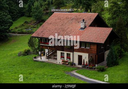 Vue d'une belle maison de chalet alpin en bois avec un beau jardin coloré et une clôture capturée à Aareschlucht, Suisse. Banque D'Images