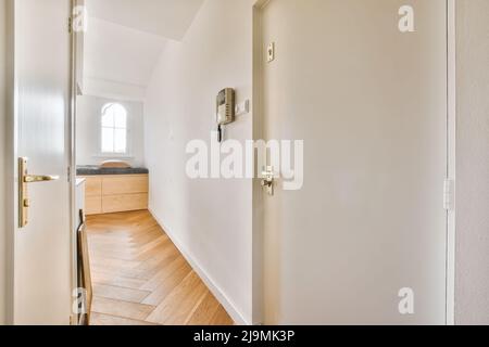 Étroit couloir vide avec portes et murs blancs dans le style minimaliste maison moderne à la lumière du jour menant à la salle de séjour Banque D'Images