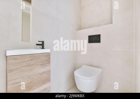 toilettes en céramique blanche placées au mur dans la salle de bains élégante avec lavabo Banque D'Images