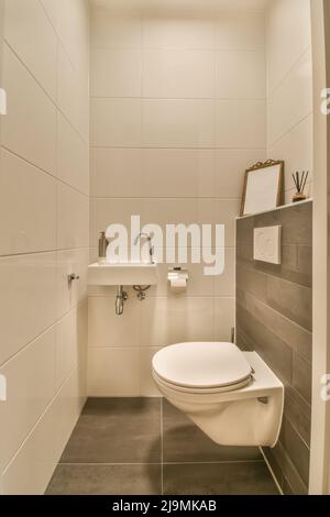 toilettes en céramique blanche placées au mur dans la salle de bains élégante avec petit lavabo Banque D'Images