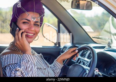 jeune belle fille africaine violet turban sur la tête usant navigateur sur l'été océan vacances trip.indian femme parlant par téléphone assis en voiture Banque D'Images